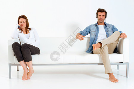 在沙发上看电视的分居夫妇成年人男人异性恋赤脚异性日常生活耳机同居牛仔裤女士图片