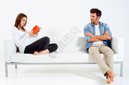 一对分居夫妇在沙发上的女人 在看一本书图片
