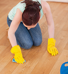 迷人的红头发女人在跪下时打扫地板图片