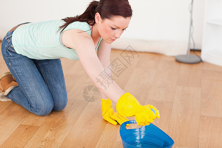 可爱的红头发女人在跪下时打扫地板图片