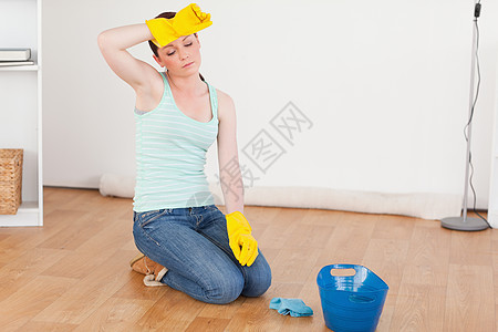 漂亮的红头发女人在打扫地板时休息了一下图片