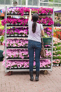 女人从架子上摘花区系快乐零售中心顾客微笑女士植物花园篮子图片