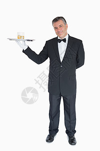 带着威士忌杯子托盘的微笑服务员图片