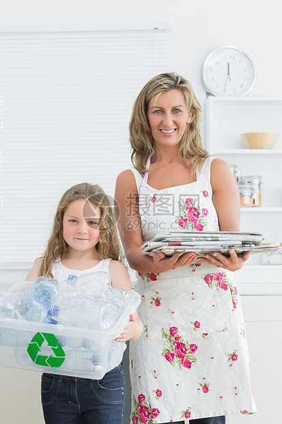 母亲和女儿在厨房里站着 浪费垃圾以回收图片