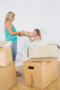 母亲和女儿带着移动的盒子微笑图片