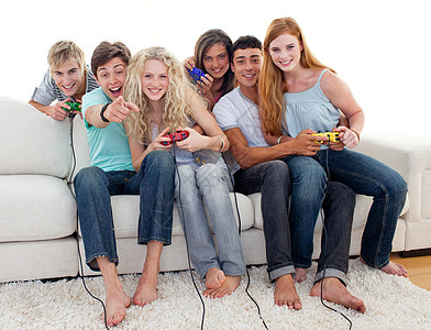 在客厅玩电子游戏的友人控制器男性青少年视频电脑享受娱乐男人乐趣女性图片