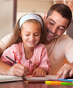 快乐的父亲帮助她的女儿做家庭功课图片