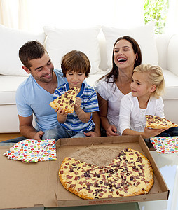 父母和孩子在客厅吃比萨享受女孩爸爸食物房间女士兄弟妈妈幸福男人图片