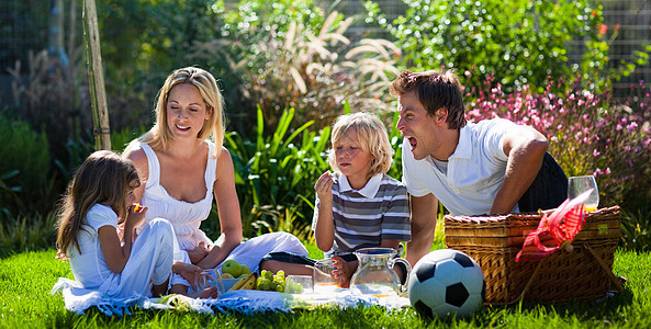 年轻家庭在野餐中玩乐孩子们幸福金发公园闲暇父亲男人母亲假期桌子图片