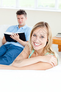 女朋友在她男朋友看书时 对着镜头微笑图片