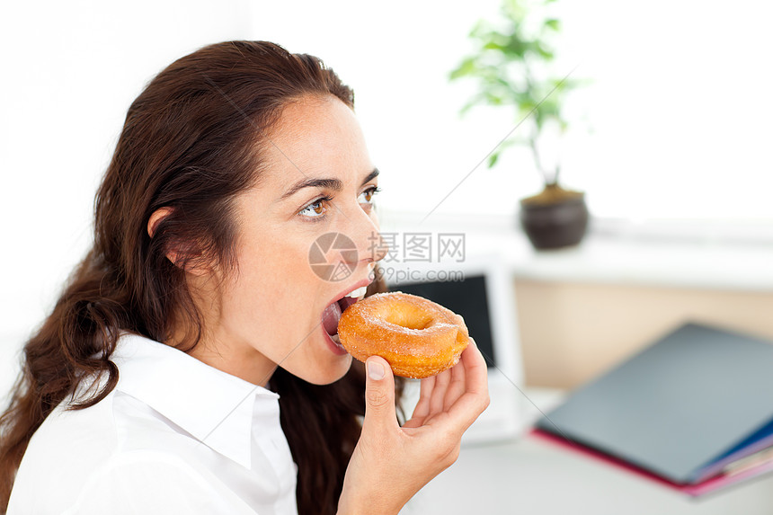 甜甜圈吃着甜甜圈的可爱的西班牙女商务人士图片