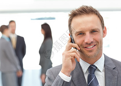 欢乐的商务人士在他的团队工作时在电话上聊天图片