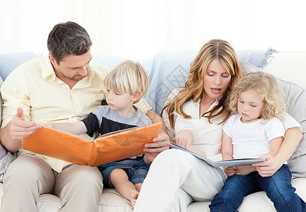 家人在沙发上读书喜悦房间女孩们女儿微笑拥抱男孩们家庭后代幸福图片