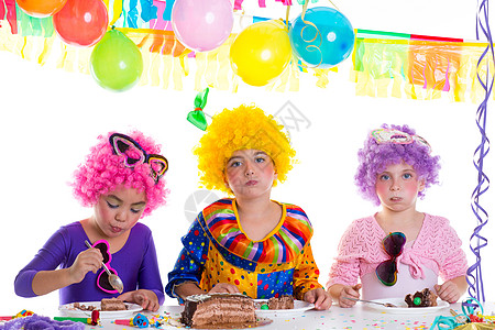 小丑气球孩子们生日派对快乐 吃巧克力蛋糕的小孩糕点享受手势生日裙子女孩派对纸屑蛋糕假发背景