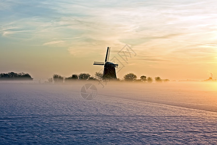寒冬下着雾和雪的黄昏时传统风车图片