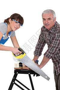 父亲和女儿在木板上锯锯木图片