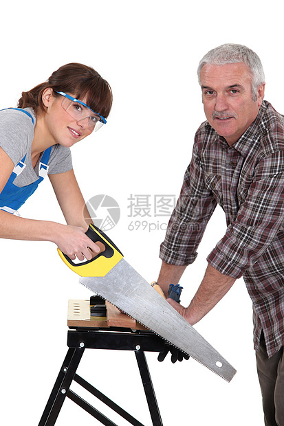 父亲和女儿在木板上锯锯木图片