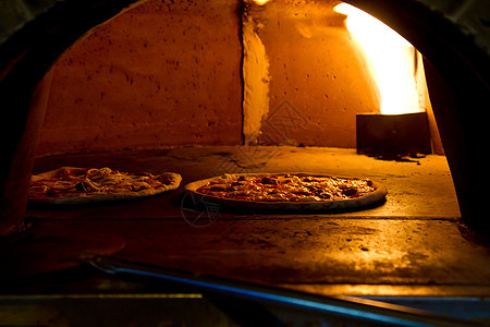 在烤炉里烘烤比萨美食糕点餐厅厨房烤箱午餐烹饪文化烧伤火炉图片