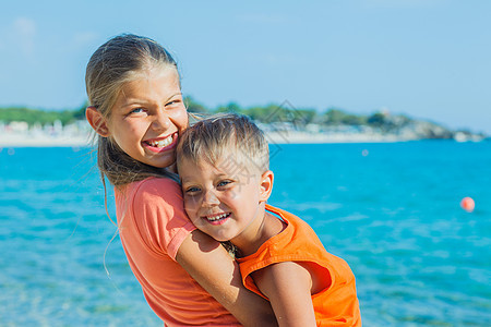 在海滩上微笑快乐的孩子女孩冒充蓝色家庭乐趣海洋金发假期阳光太阳图片