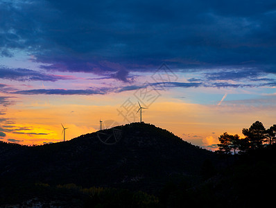 有电风车的日落山涡轮活力阴影气氛树木蓝色旋转发电机环境螺旋桨图片