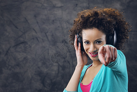 享受音乐的年轻妇女女子女性青少年黑发卷发耳机微笑音频模特时装图片
