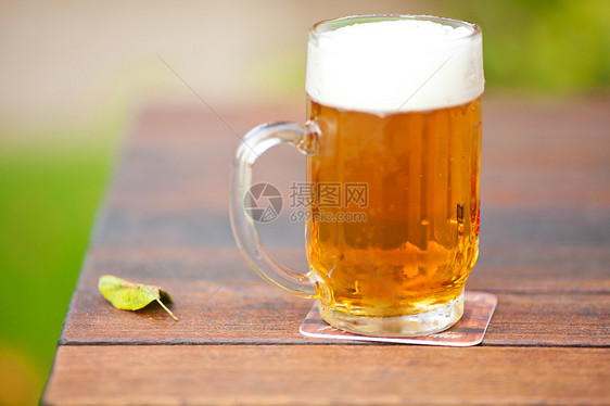 杯子上摆着轻啤酒花园酒吧金子酒精桌子庆典派对阳光琥珀色木头图片
