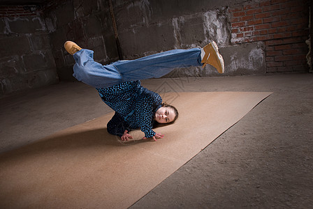 在砖墙上跳现代风格的Hipop舞者霹雳舞衣服演员情感舞蹈家蓝色牛仔裤女士说唱黑发图片