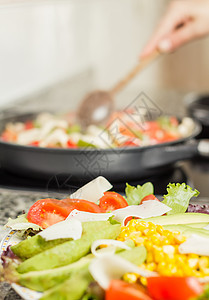 特写新鲜沙拉菜盘和女性在锅里做饭绿色平底锅蔬菜玉米片玉米沙拉食物胡椒红色洋葱图片