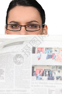 戴眼镜的妇女在报纸上观看图片
