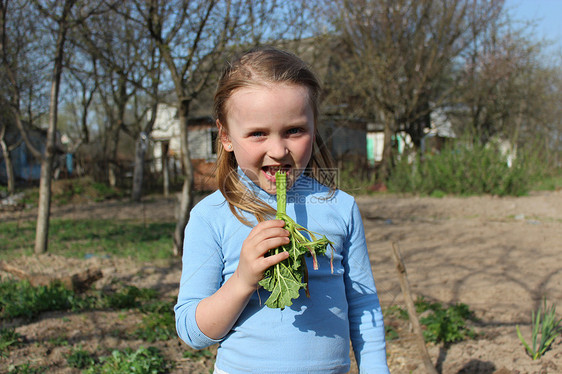 女孩在嚼着小青春的粗巴植物叶子环境孩子们树叶乐趣衣服植物学生活微笑图片
