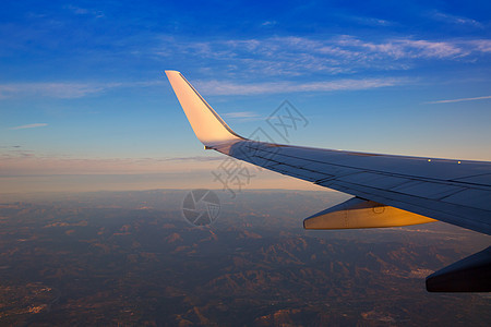 日落时空飞机喷气机翼 有金色阳光太阳翅膀积雨旅行运输涡轮青色土地航班云景图片