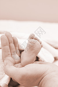 父母双手握着婴儿的腿女儿赤脚棕榈父亲脚趾家庭女孩们童年保健皮肤图片