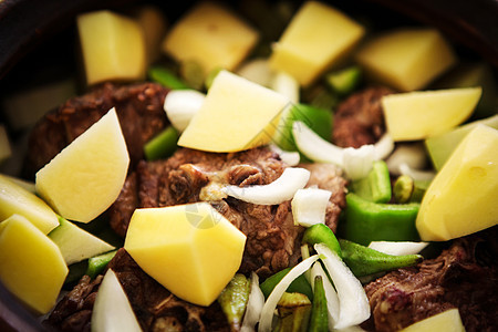 混合蔬菜的羊肉炖菜土豆草药食物烹饪钢包洋葱水平金属勺子羊肉图片