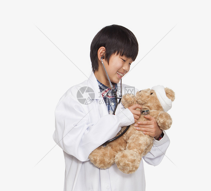 男孩打扮成医生检查泰迪熊的生命征兆图片