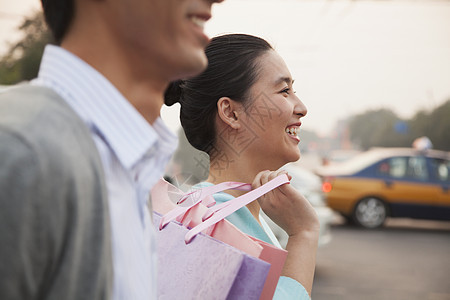 一对年轻夫妇在北京街上 拿着购物袋走来 特写女性头肩幸福年轻人女朋友休闲团结零售活动购物图片