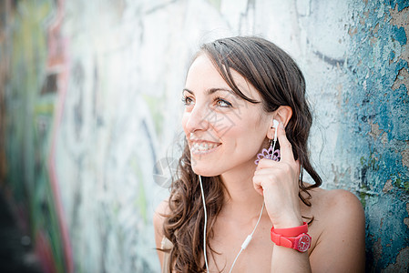 听音乐的美容女子音乐播放器放松女士街道音乐微笑城市幸福耳机图片