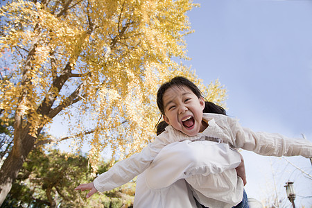 祖父和外孙女在公园玩耍树区黑发季节俏皮亲热家庭视图呐喊银杏树拥抱图片