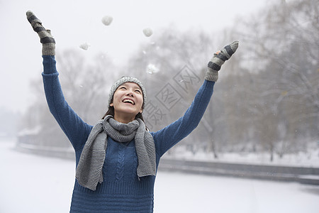 年青女性在雪雪中玩耍图片