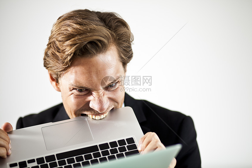 男人在沮丧中咬笔记本电脑图片