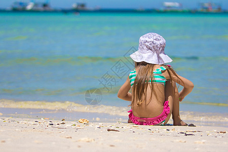 穿泳装的小女孩穿泳衣的可爱小女孩 在热带海滩玩游泳服喜悦乐趣泳装海岸假期支撑白色异国婴儿情调背景
