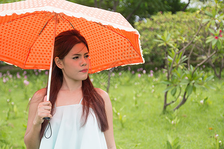 年轻妇女和橙色雨伞假期人脸幸福公园微笑露齿橙子成人女性图片