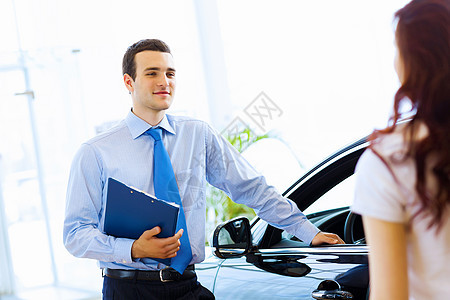 在汽车沙龙的年轻女子职业兜帽服务客户销售合同零售顾问咨询夫妻图片