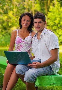夫妇在公园里用笔记本电脑坐在一对夫妇旁边图片