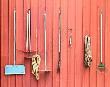 农业工具挂在红色谷仓墙上图片