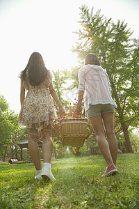 两个朋友走进公园野餐 在春日带一个野餐篮子 后方观望图片