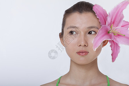 年轻美女的肖像 粉红色大花朵夹在她耳后 摄影棚拍摄图片