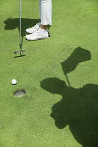 在高尔夫球场上打球的年轻女子 低层 专注在洞口活动高尔夫球部位竞技体育女性人体草皮推杆摄影图片