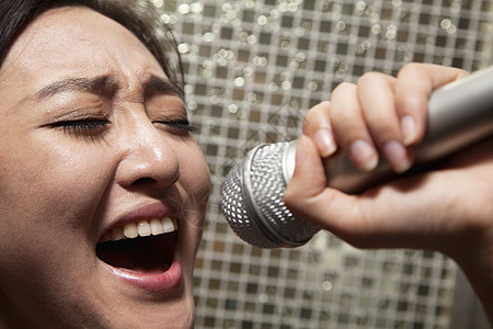 在卡拉OK的卡拉OK 女青年在麦克风中歌唱嘴巴音乐派对活动水平女性娱乐歌手夜生活休闲背景图片