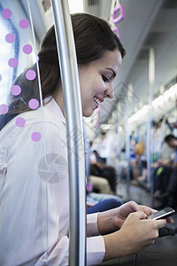 坐在地铁上并使用手机的女青年商业妇女图片