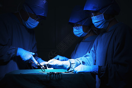 在手术台上拿着手术设备并工作的外科医生团队图片